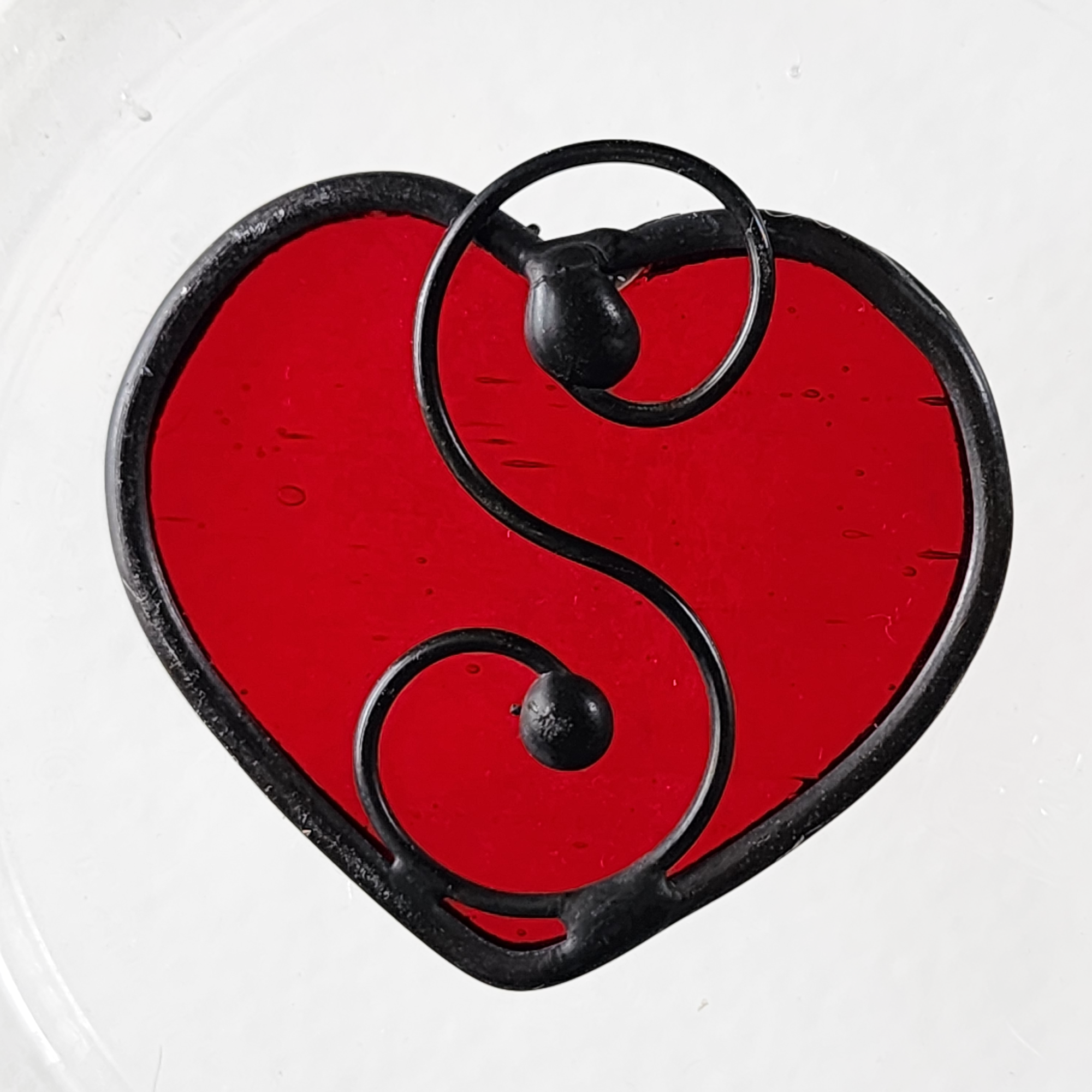 Red heart-shaped stained glass suncatcher charm on a white 
