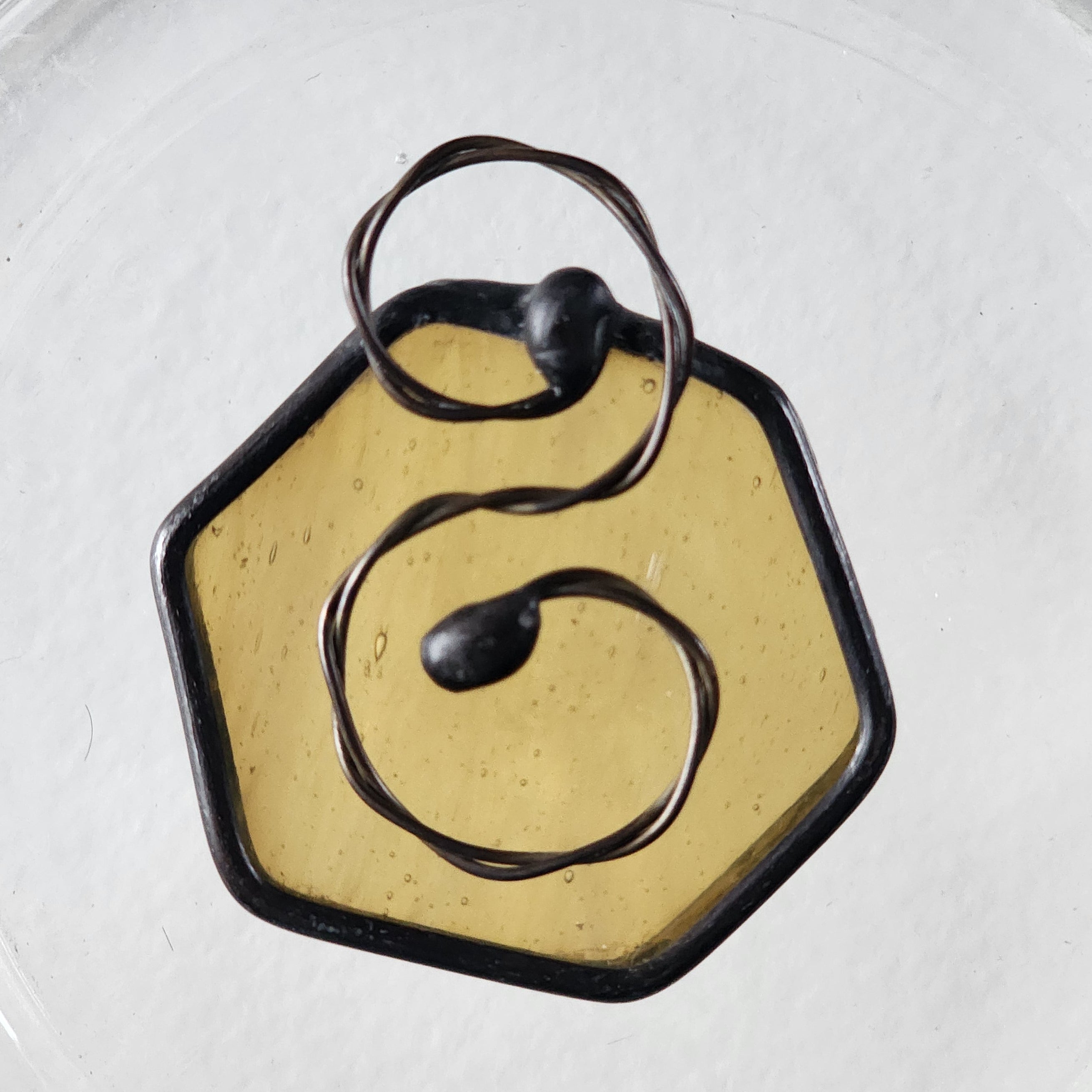 Seedy amber stained glass hexagon charm suncatcher with twisted wire scroll