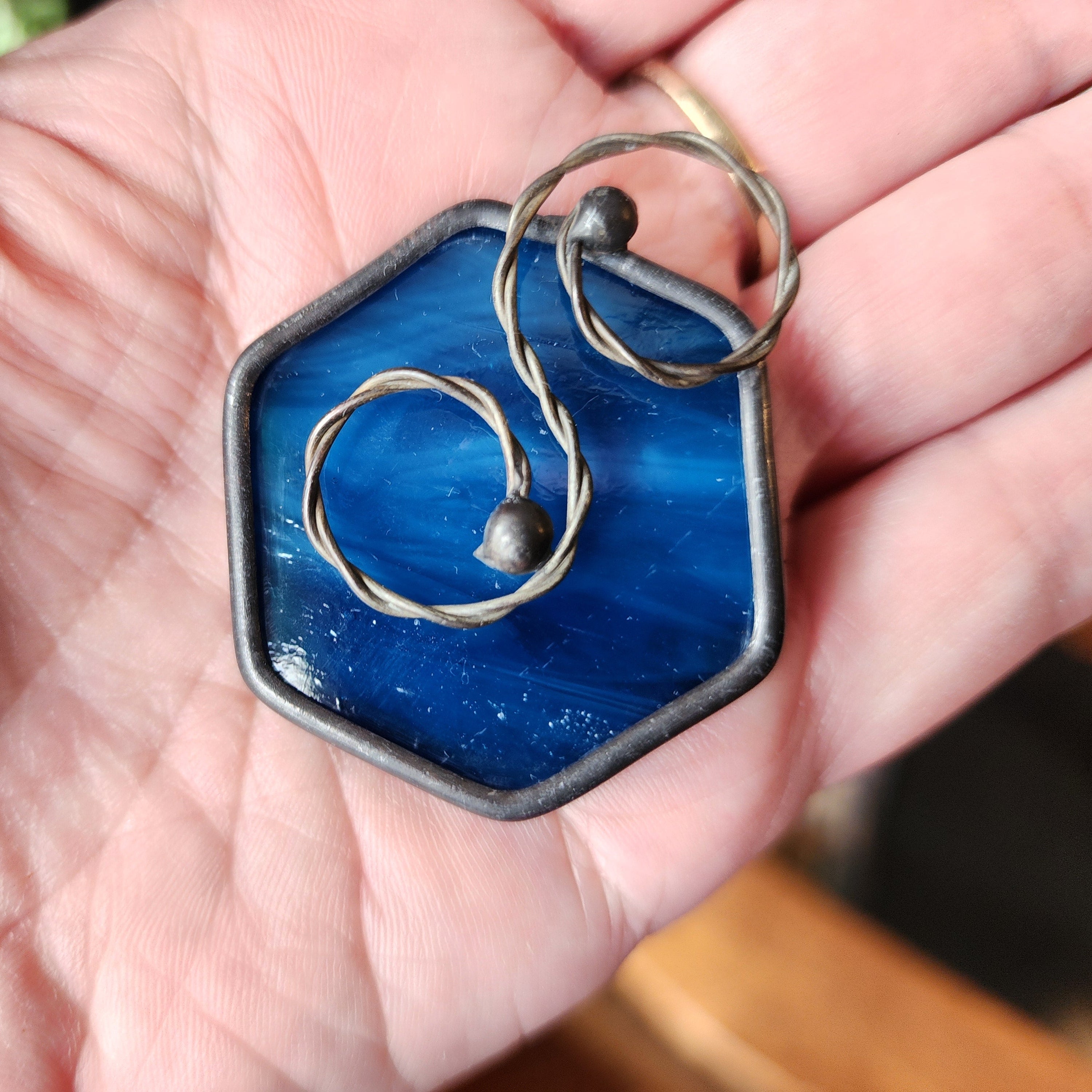 Blue mini hexagon stained glass suncatcher car charm held in a hand