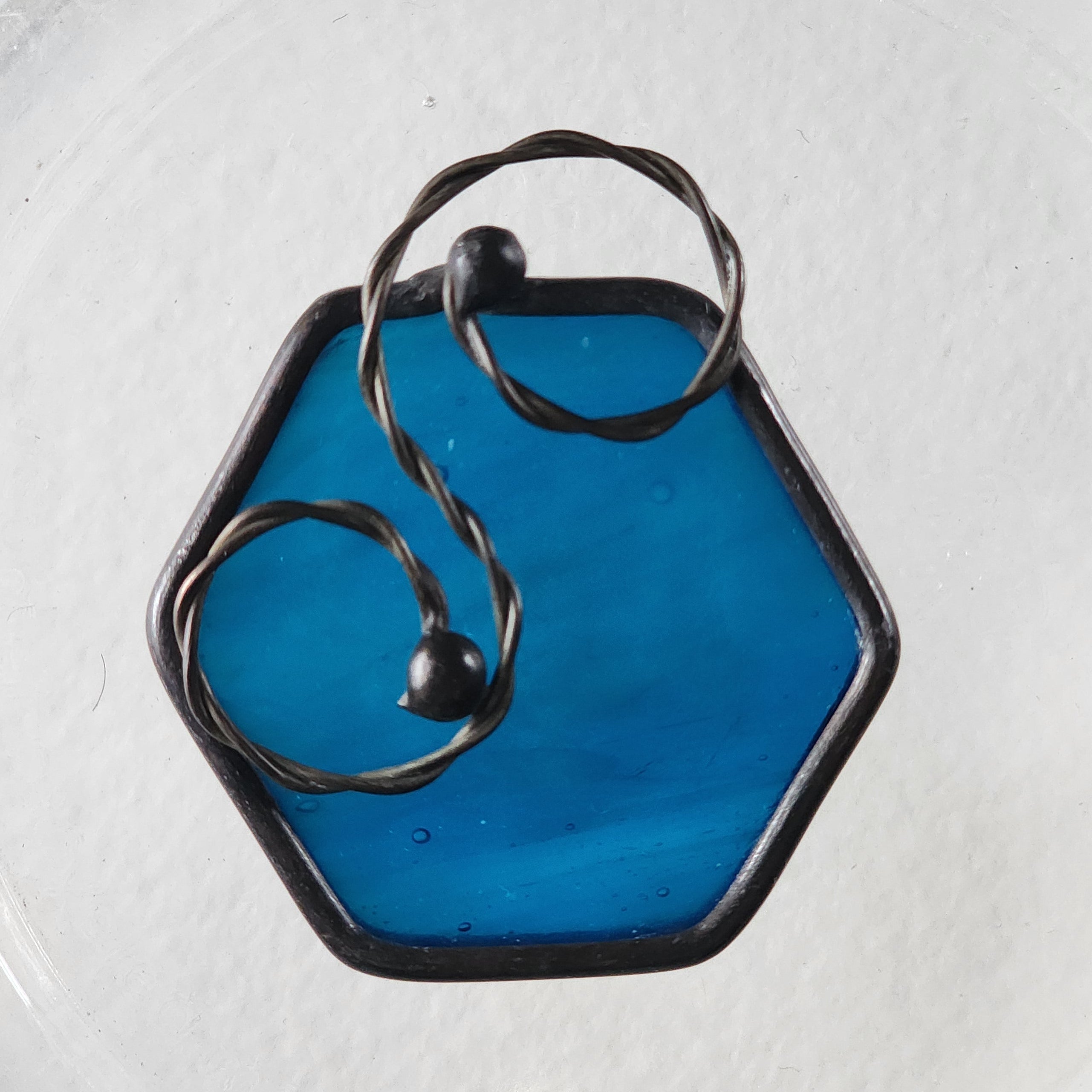 Streaky blue stained glass hexagon charm suncatcher with twisted wire scroll