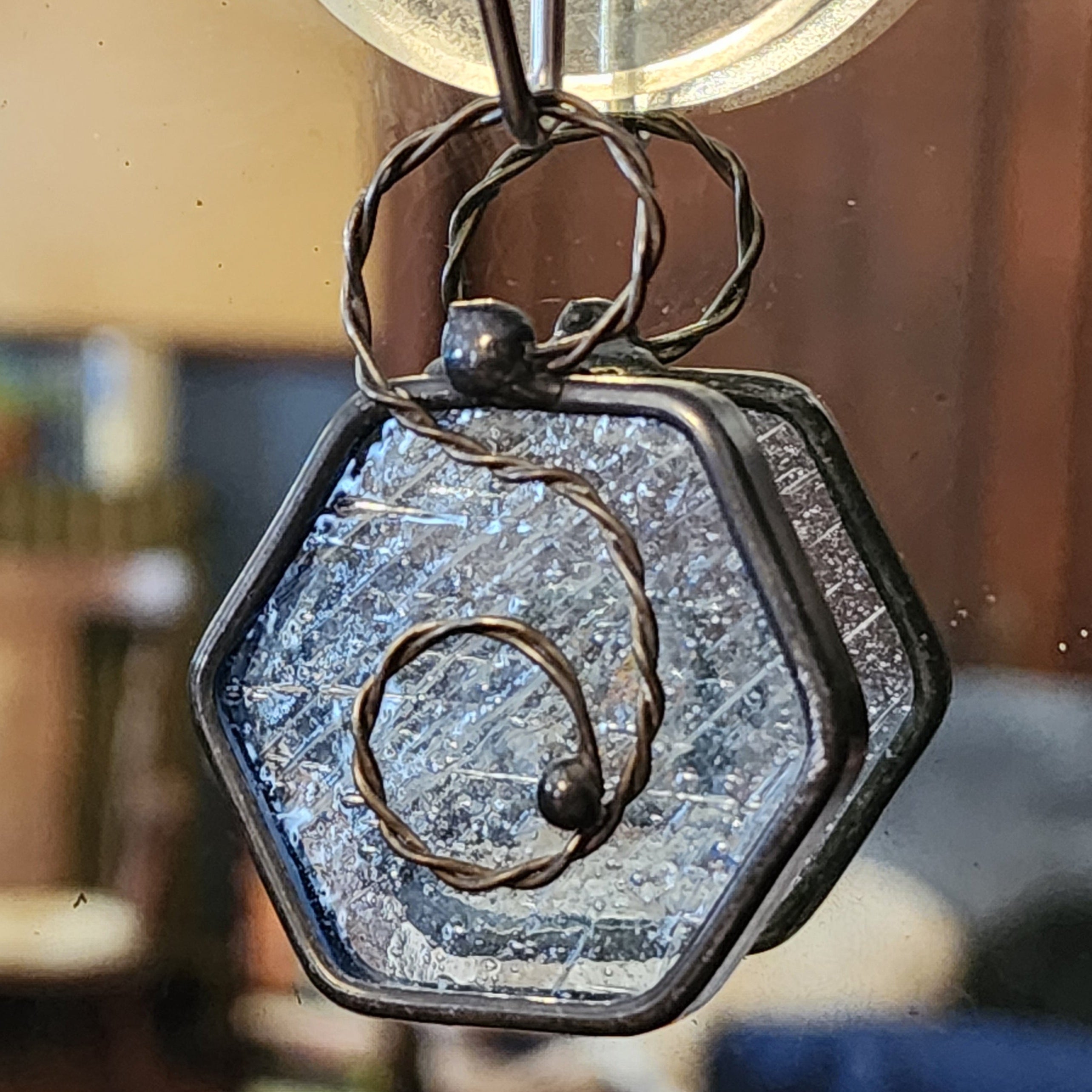 Clear mini hexagon stained glass suncatcher car charm hanging indoors.