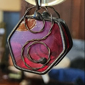 Red mini hexagon stained glass suncatcher car charm on a blurred background
