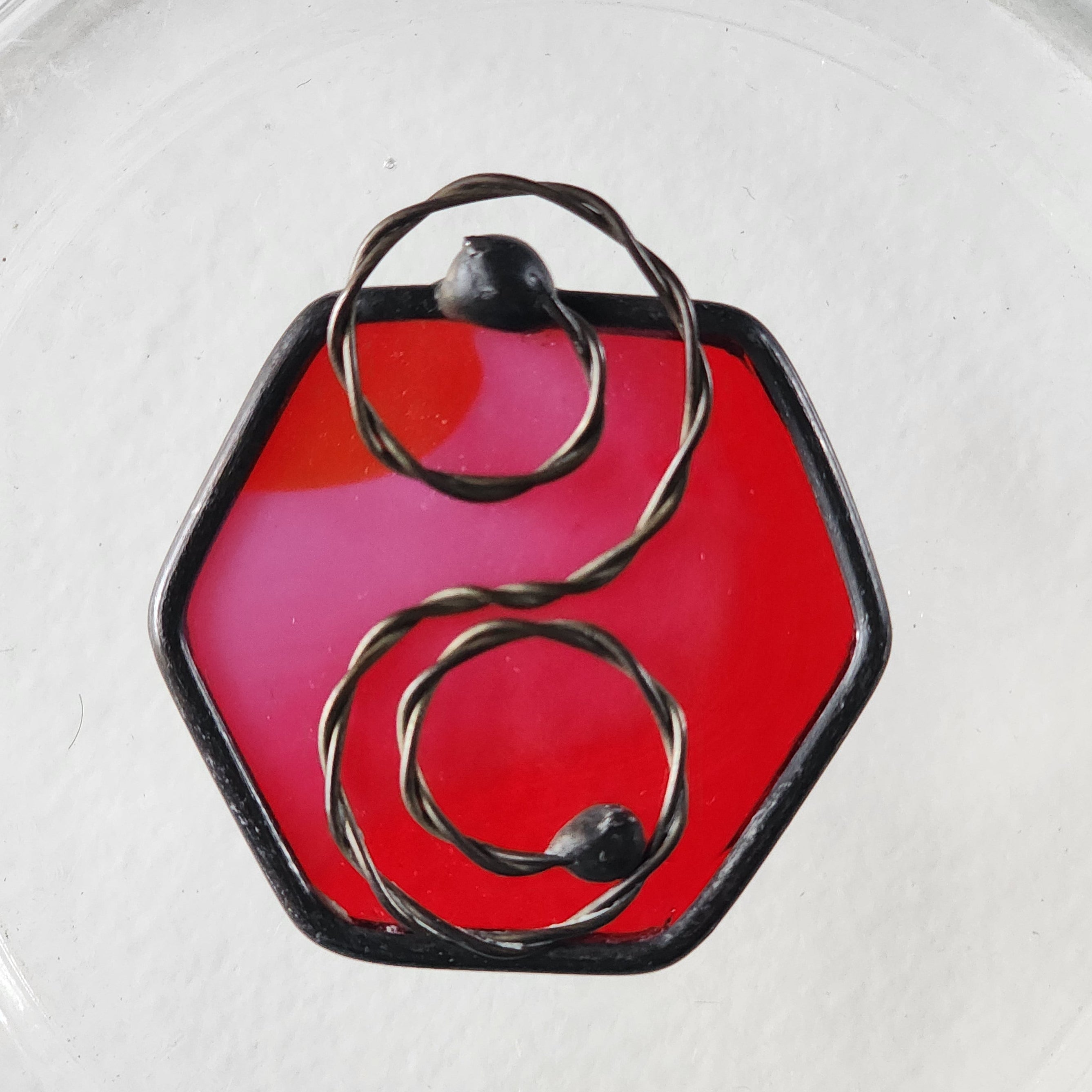 hexagon red suncatcher charm and metal scroll on a white background