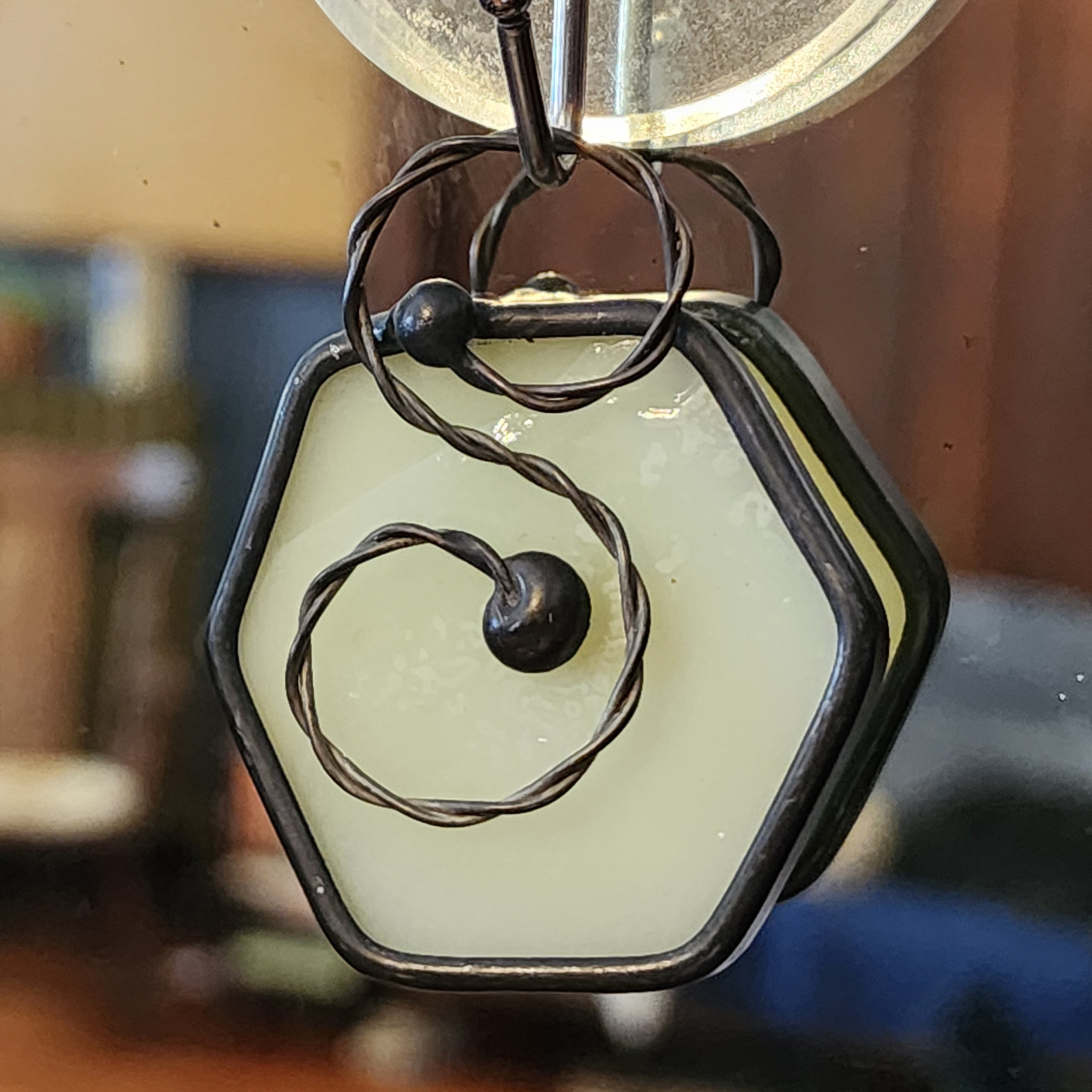 Ivory mini hexagon stained glass suncatcher car charm on a blurred indoor background