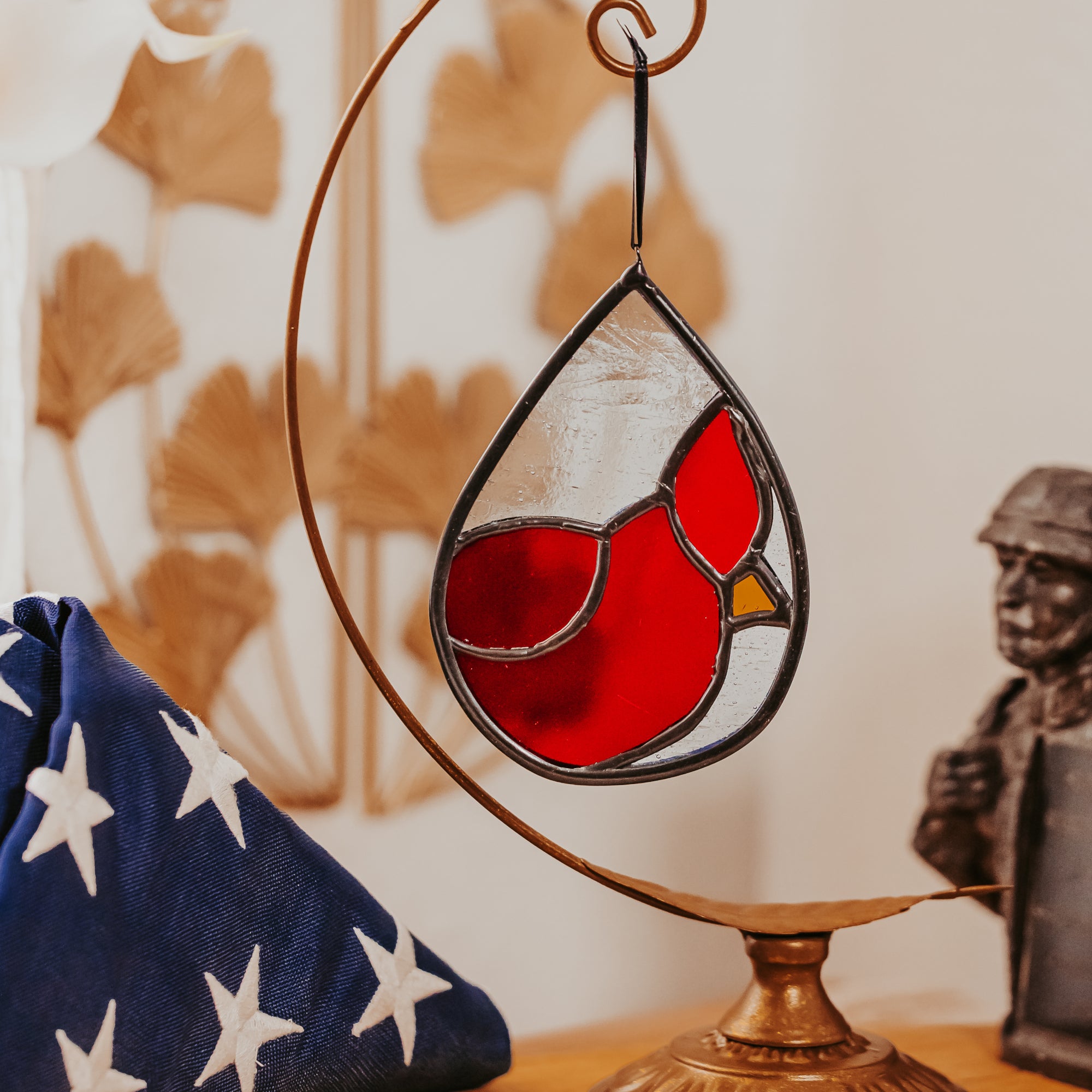 Stained glass cardinal ornament on a stand with a blurred background with patriotic elements