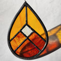 Red and orange geometric stained glass suncatcher with transmitted light on a neutral background