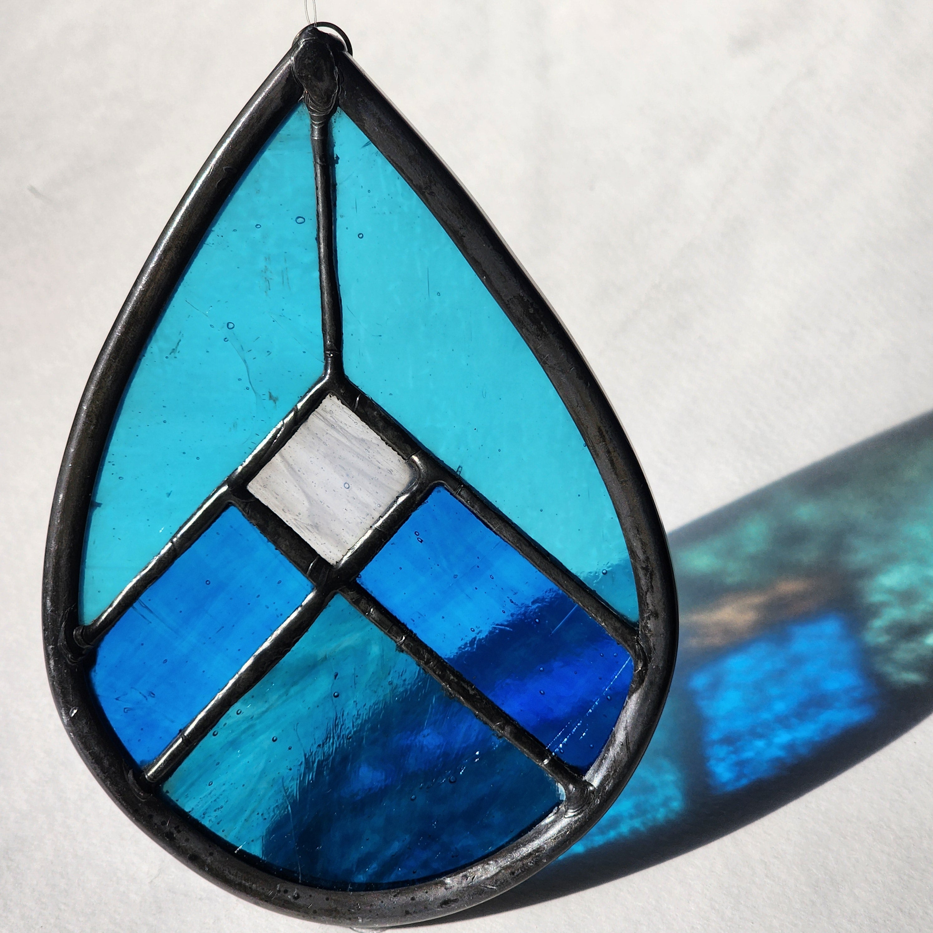 Blue geometric stained glass suncatcher with transmitted light on a neutral background
