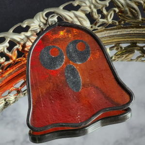 Cartoon-style stained glass ghost suncatcher in wispy red-orange textured glass with cute spooky face
