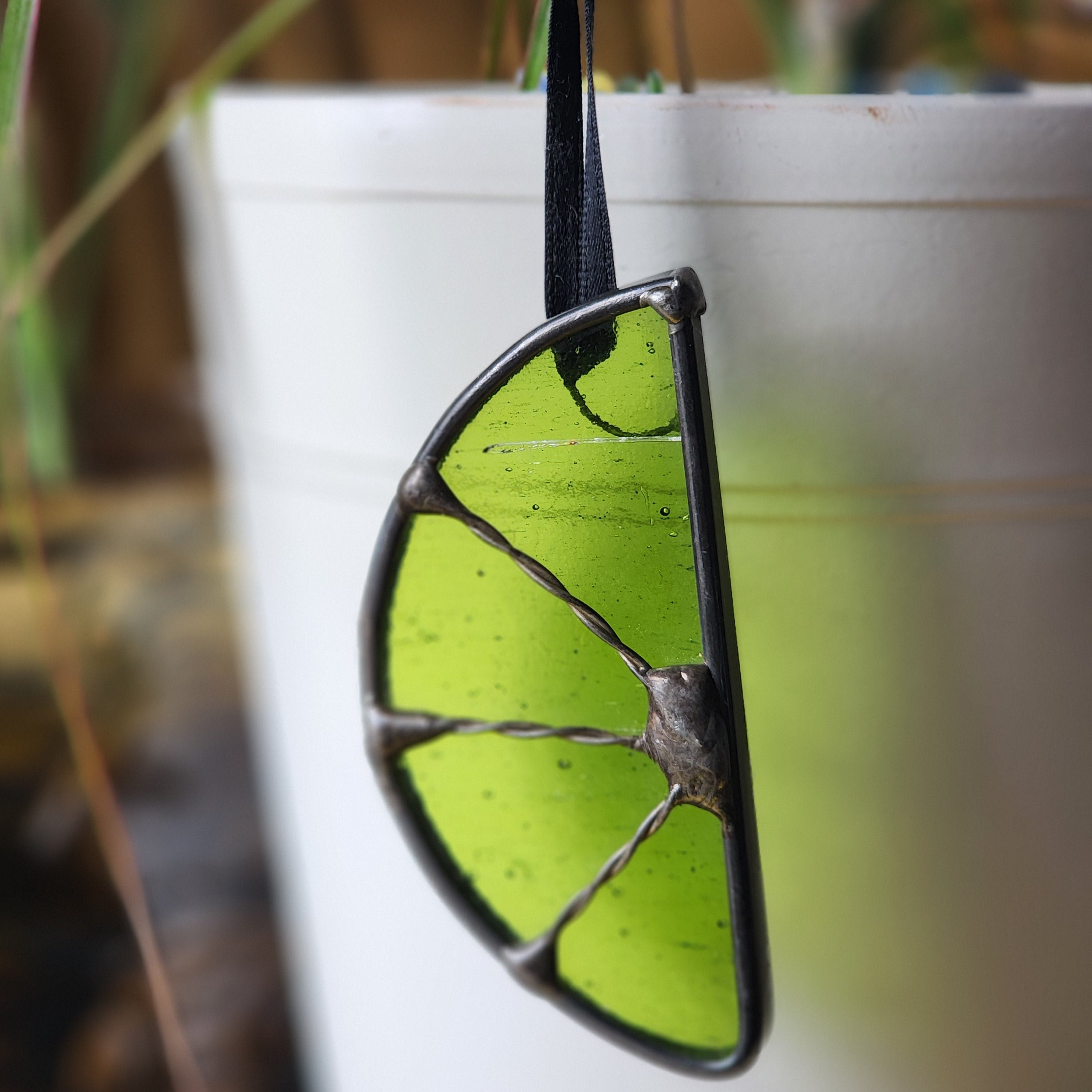 Green lime suncatcher hanging from a plant