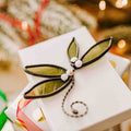 Green stained glass mistletoe with white fused glass berries and hand-twisted wire stem on holiday background