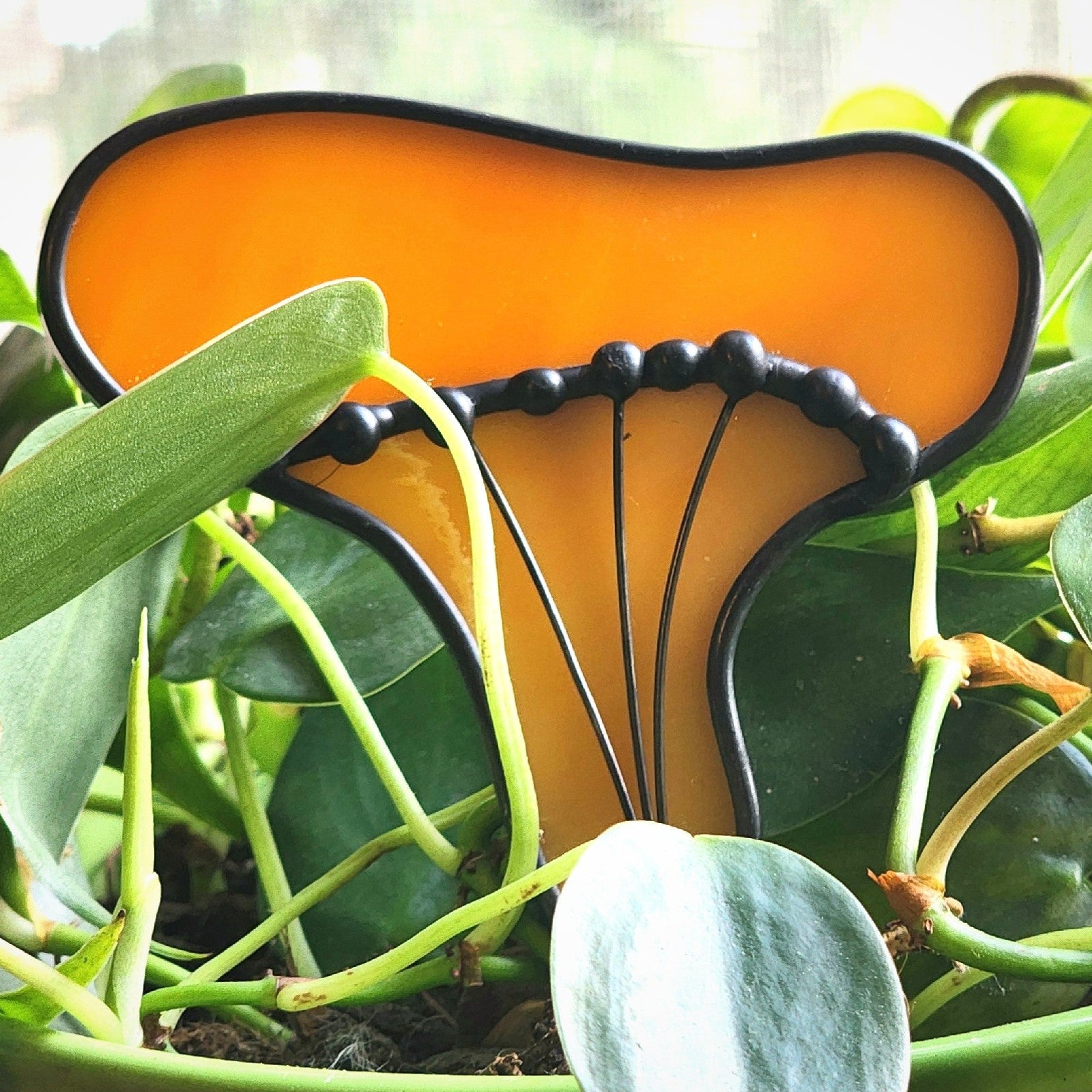 Orange chanterelle stained glass mushroom plant stake in a green potted plant