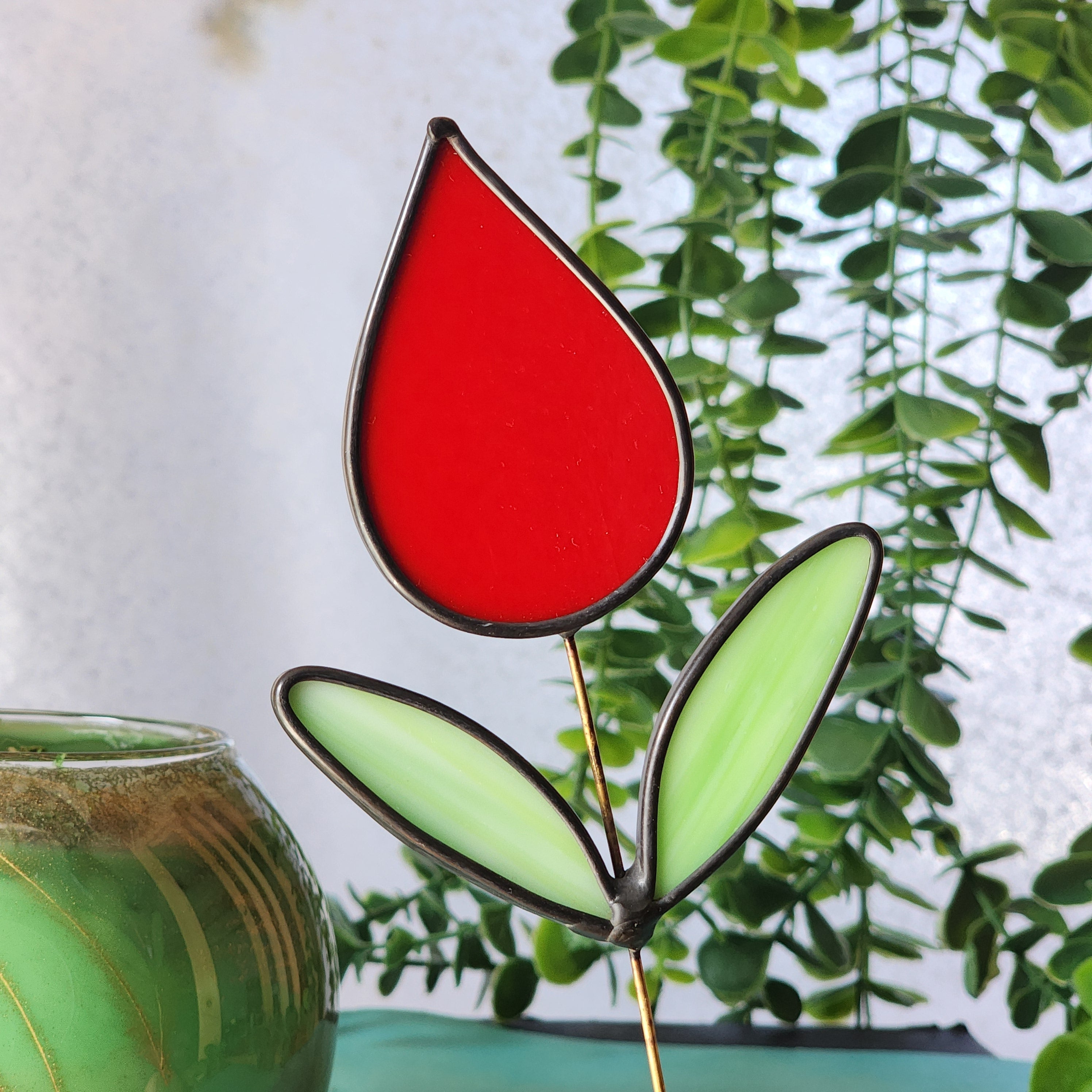 Stained glass tulip plant stake on a blurred background