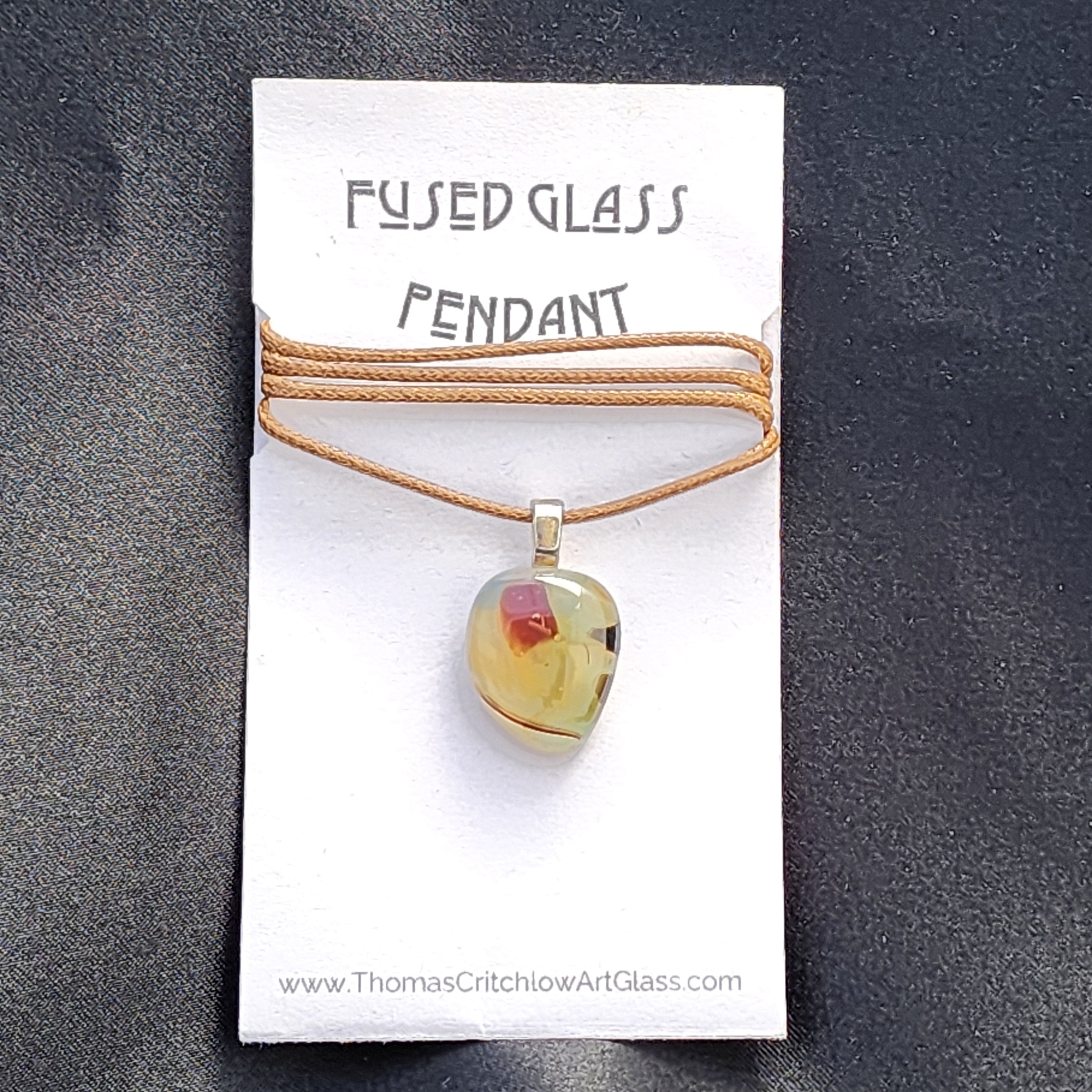 Fused glass pendant on a card with 'Thomas Critchlow Art Glass' branding.