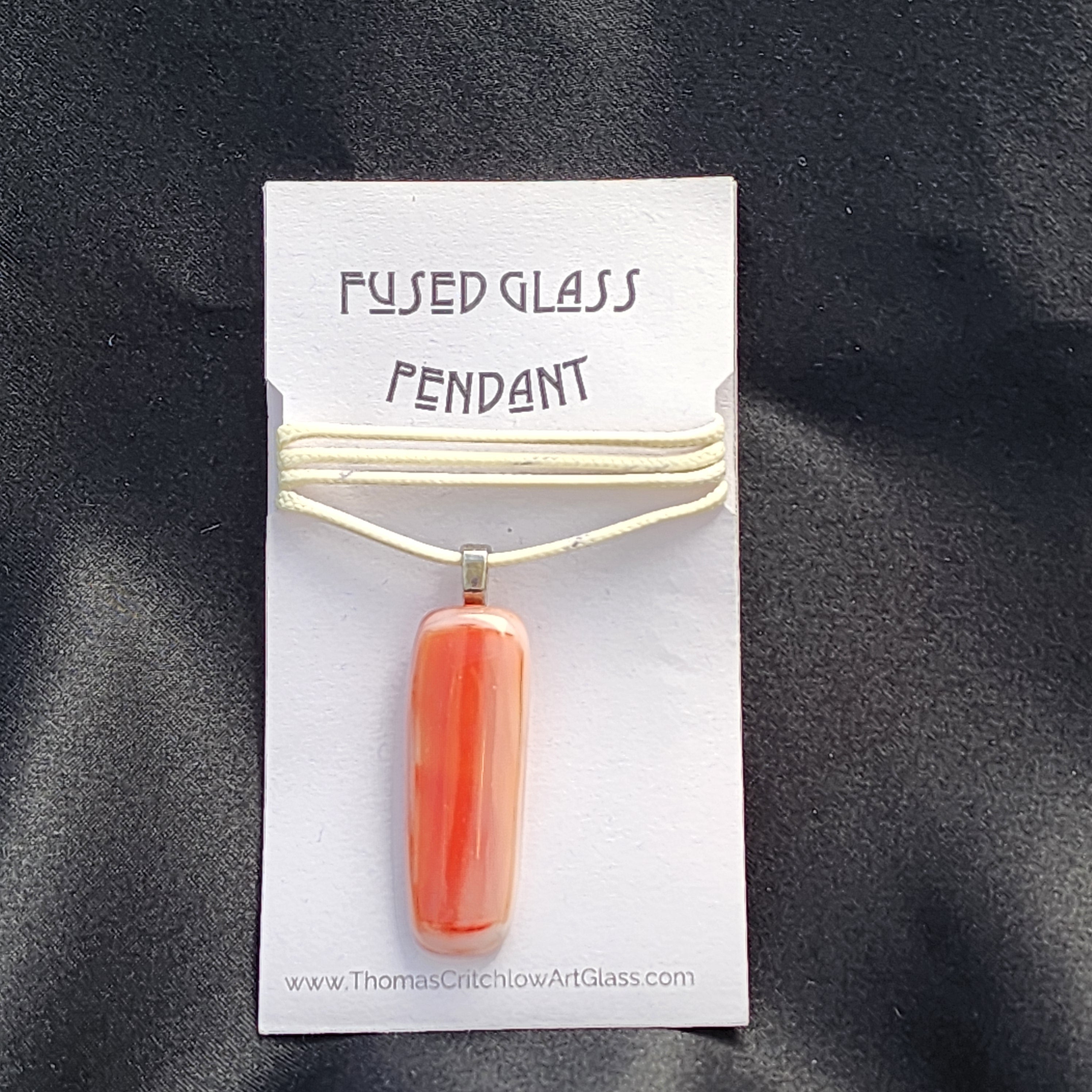 Fused glass pendant on a card with 'Thomas Critchlow Art Glass' website.