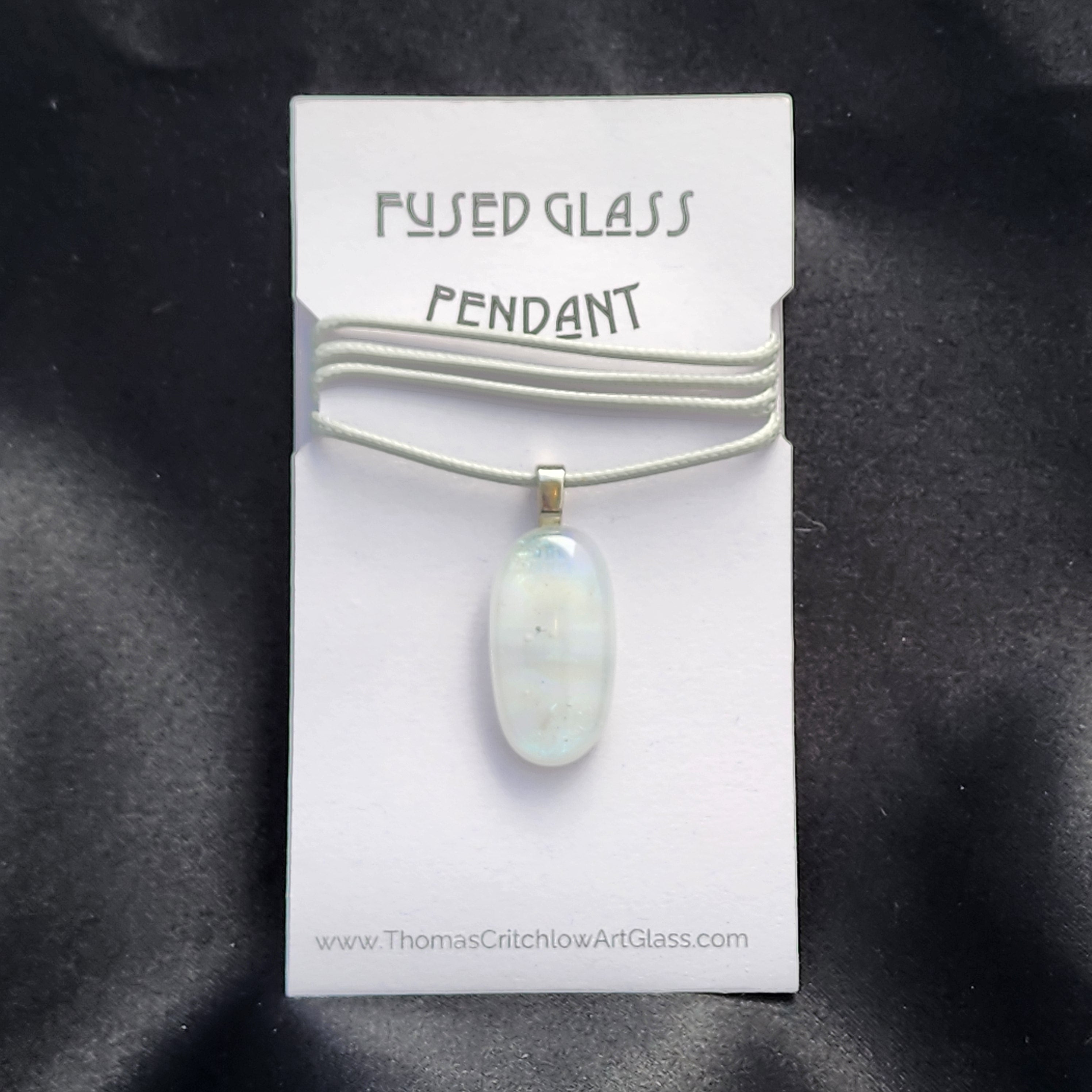 Fused glass pendant on a card with 'Thomas Cothick Art Glass' branding against a dark background