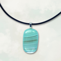 Iridescent and blue striped pendant necklace on a white background