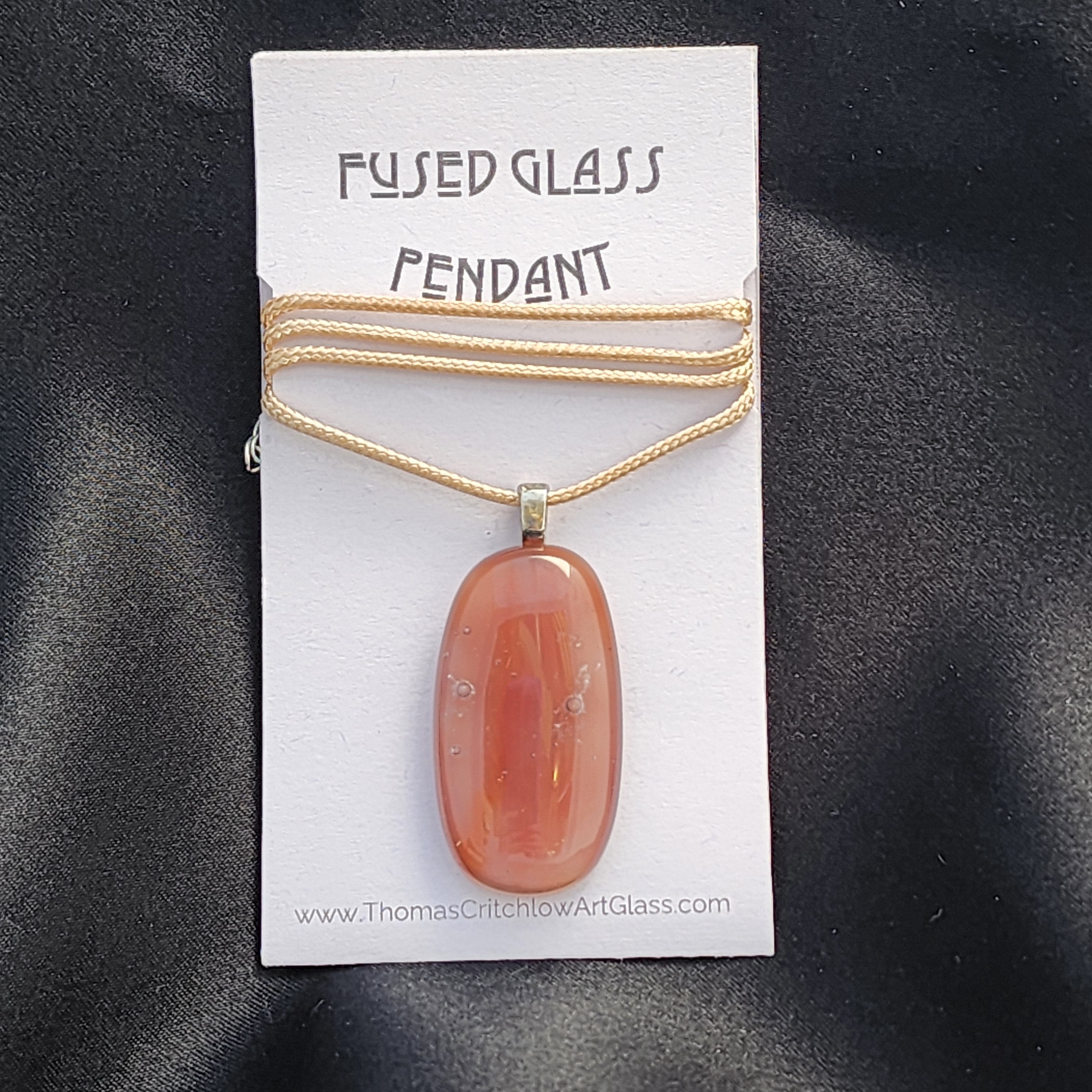 Fused glass pendant necklace on a display card with a black background