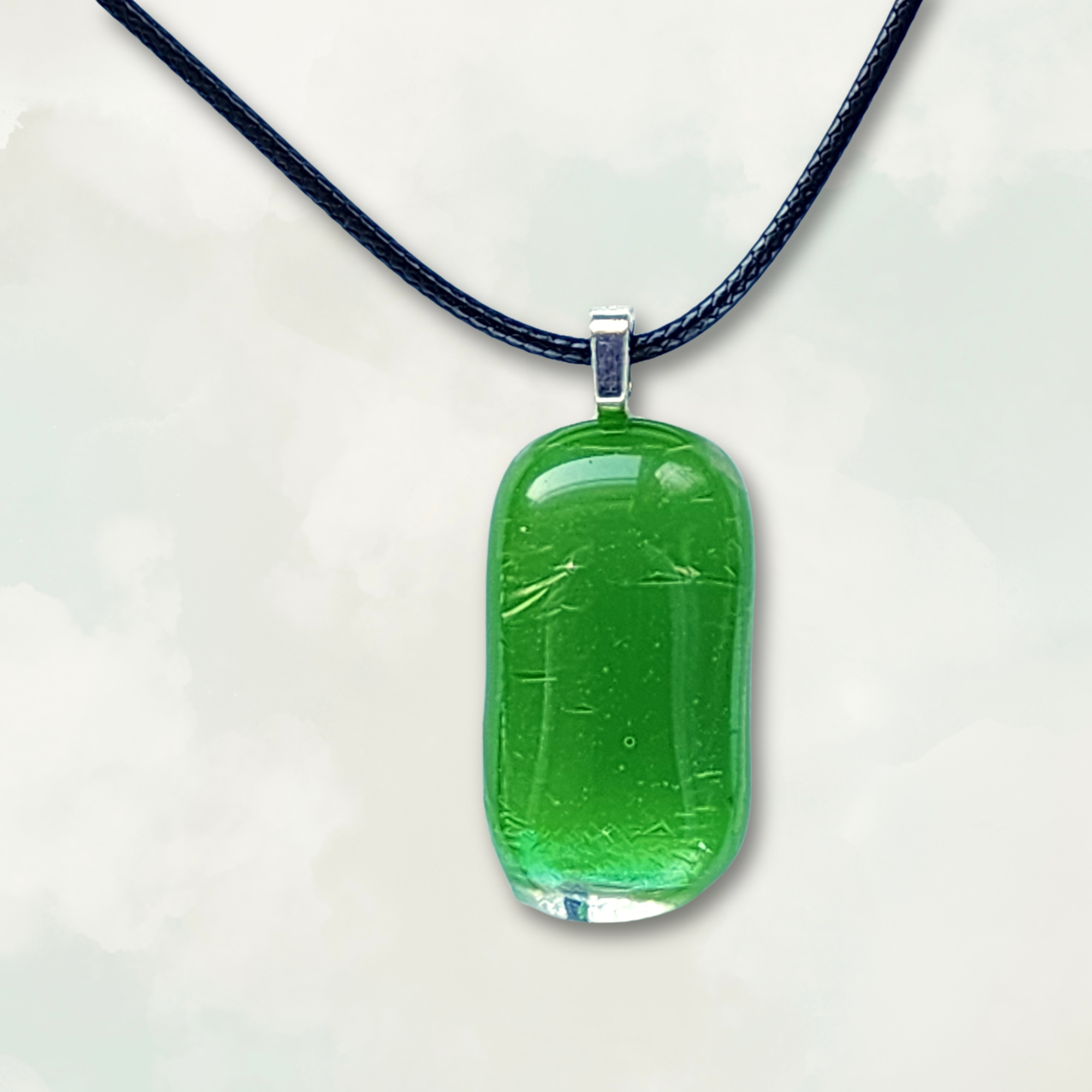 Iridescent and Fern green glass pendant on a black cord against a neutral background