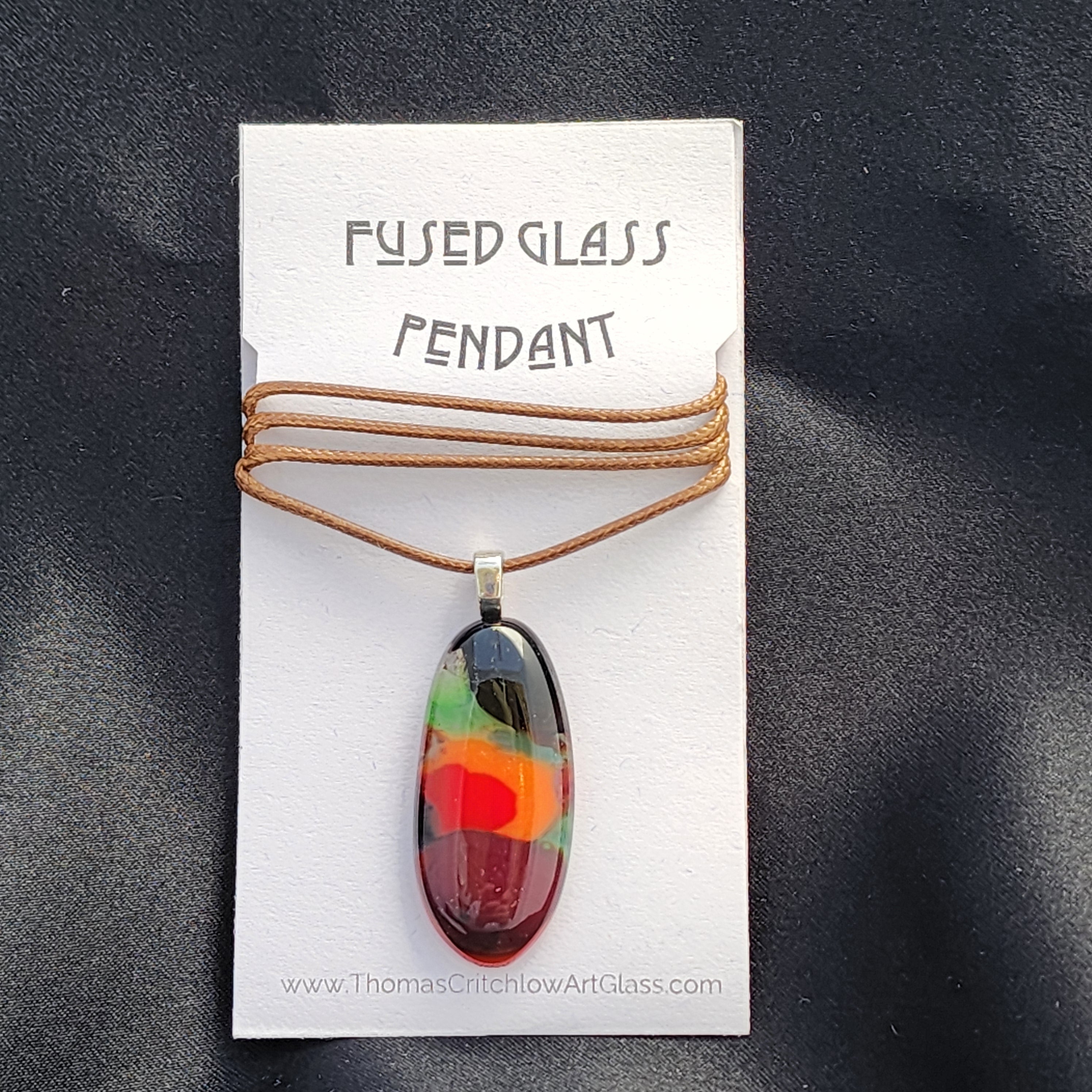 Fused glass pendant on a card with 'Thomas Chichlow Art Glass' branding.