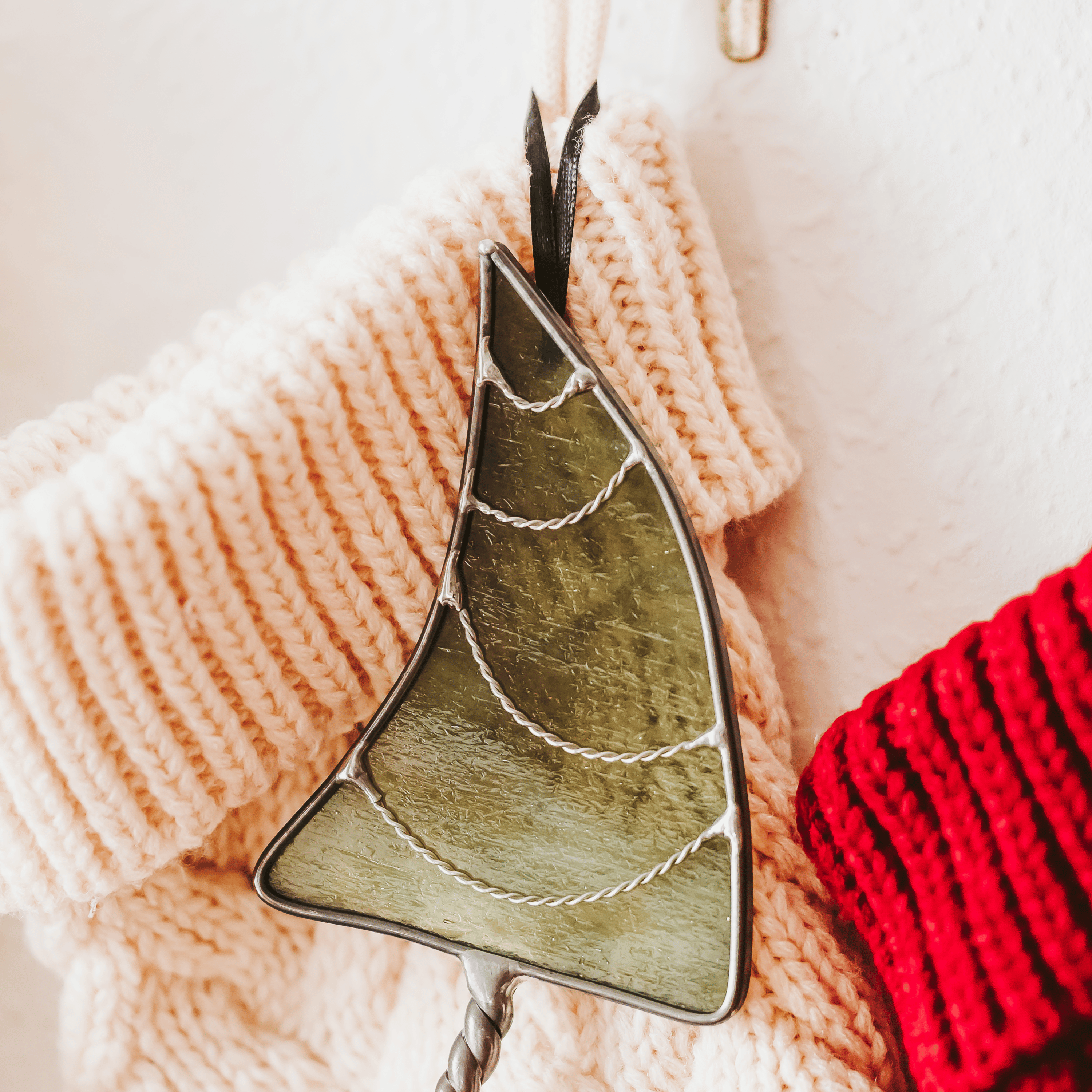 Classic green stained glass Christmas tree ornament with hand twisted metal garland and trunk on a holiday stocking