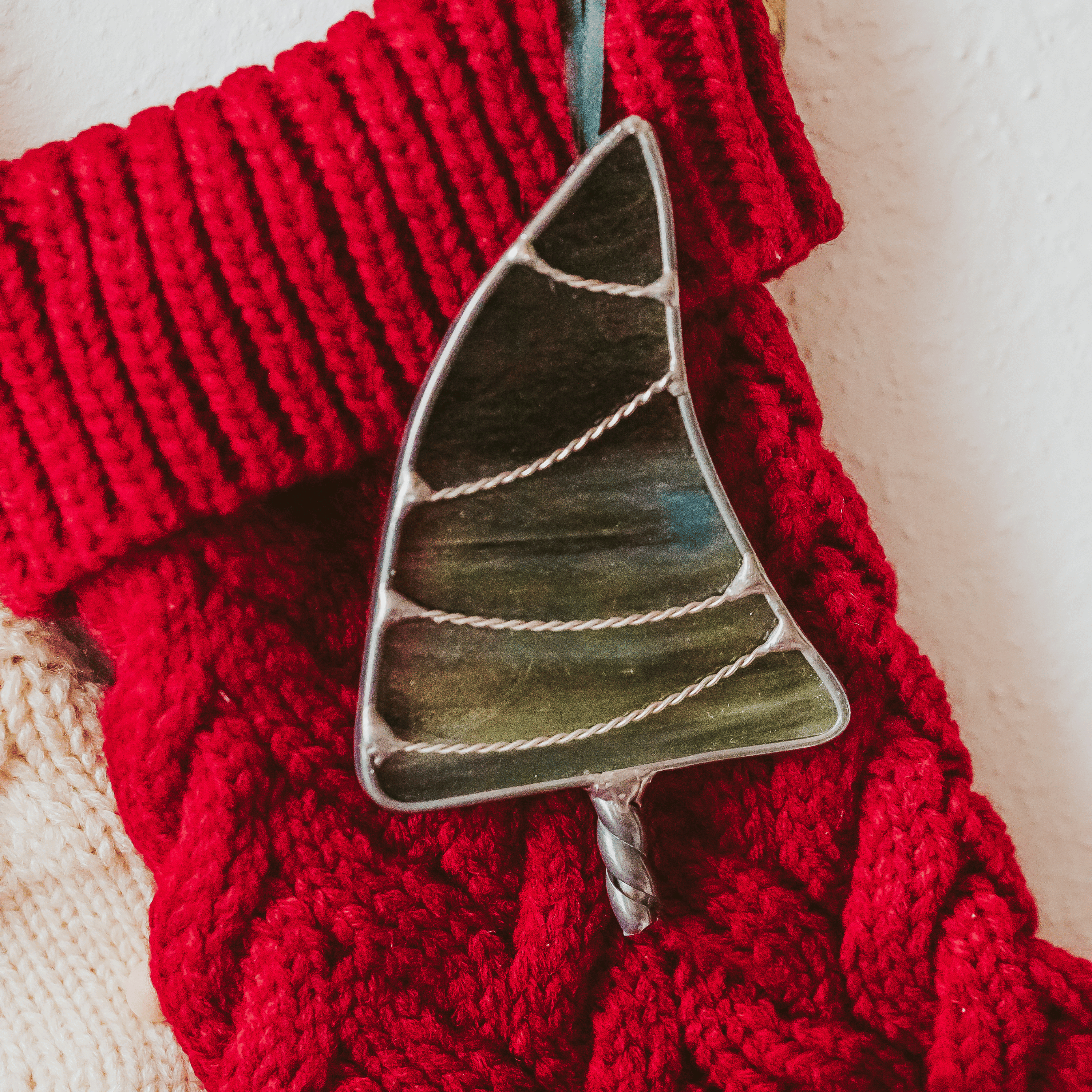 Classic green stained glass Christmas tree ornament with hand twisted metal garland and trunk on a holiday stocking