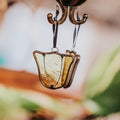 Yellow tulip stained glass suncatcher hanging against a mirrored natural background