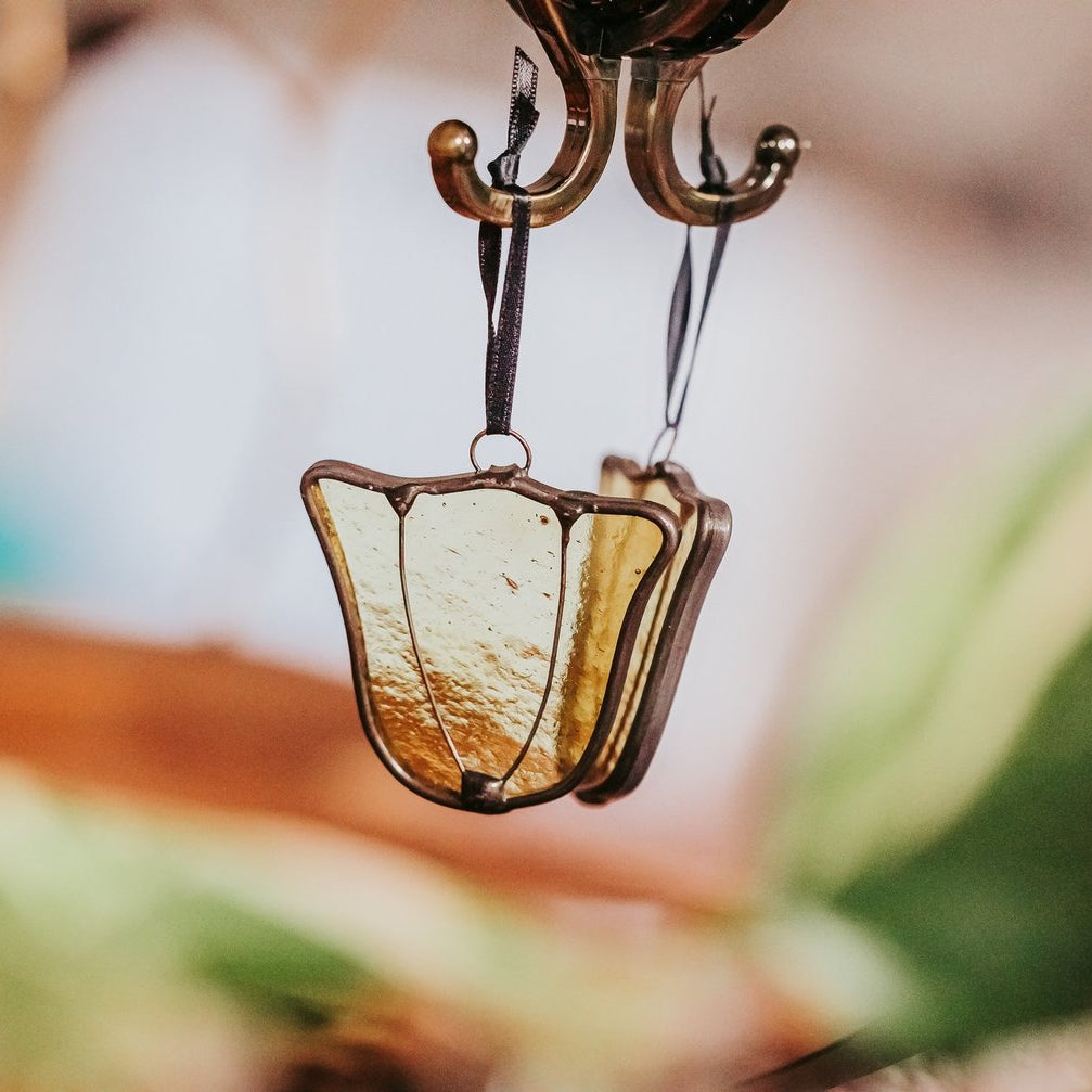Yellow tulip stained glass suncatcher hanging against a mirrored natural background