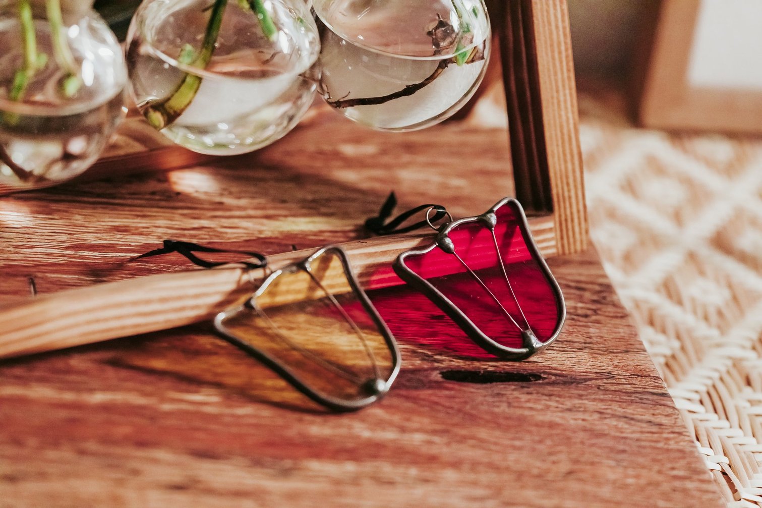 Two stained glass tulip suncatchers, one yellow and one red, against a wood background