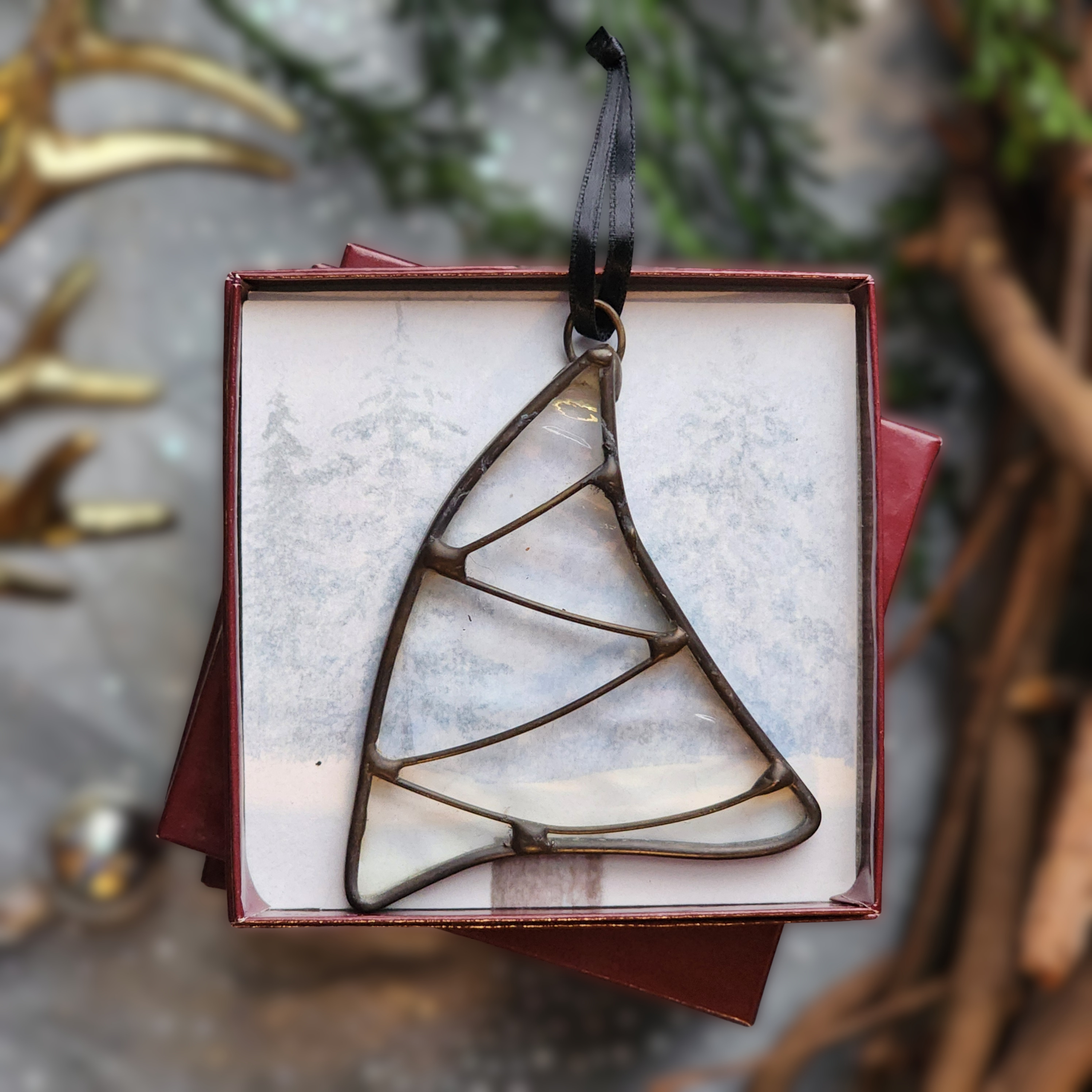 Iridescent Whimsical Christmas Tree stained glass ornament in a gift box on a festive background