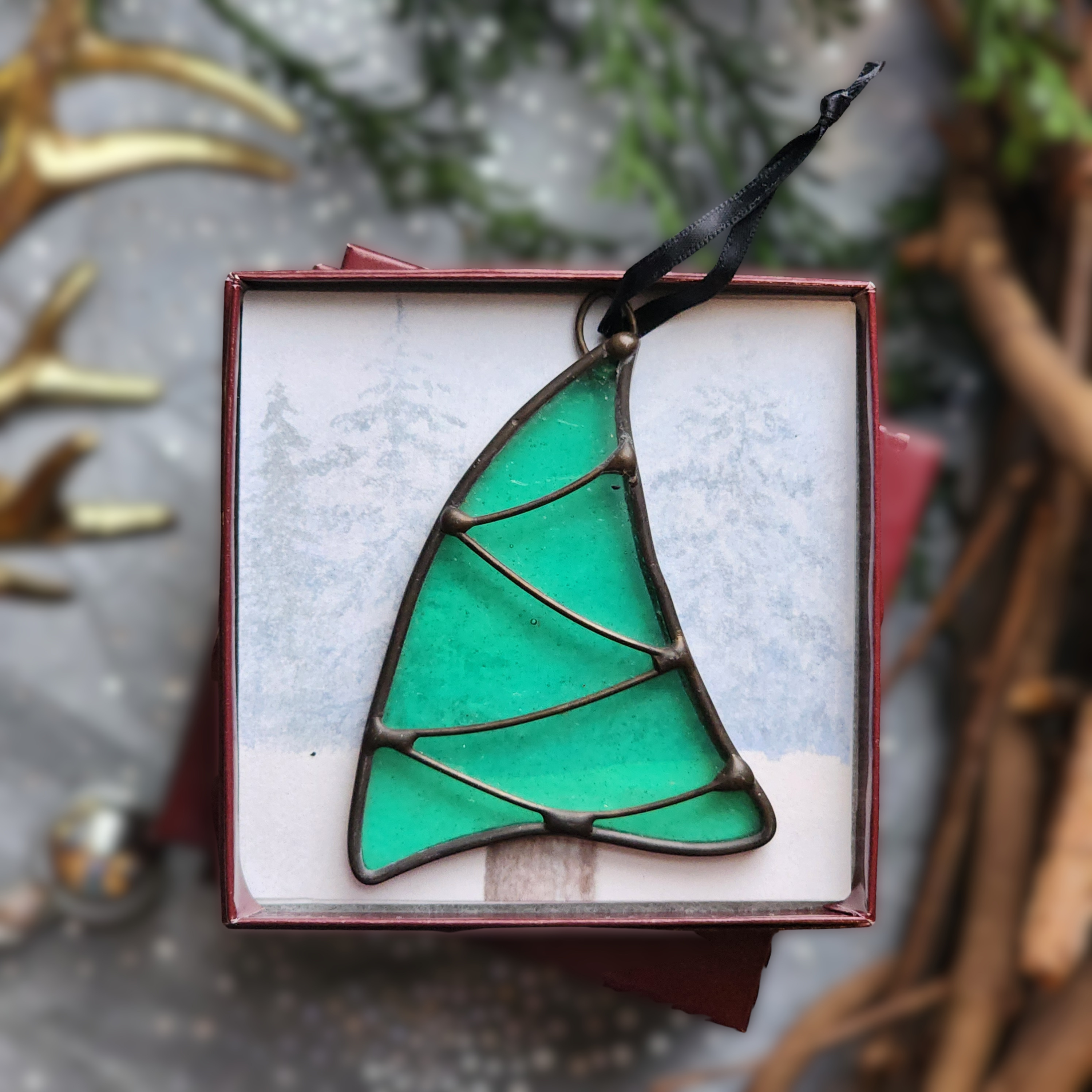 Sea Green Whimsical Christmas Tree stained glass ornament in a gift box on a festive background