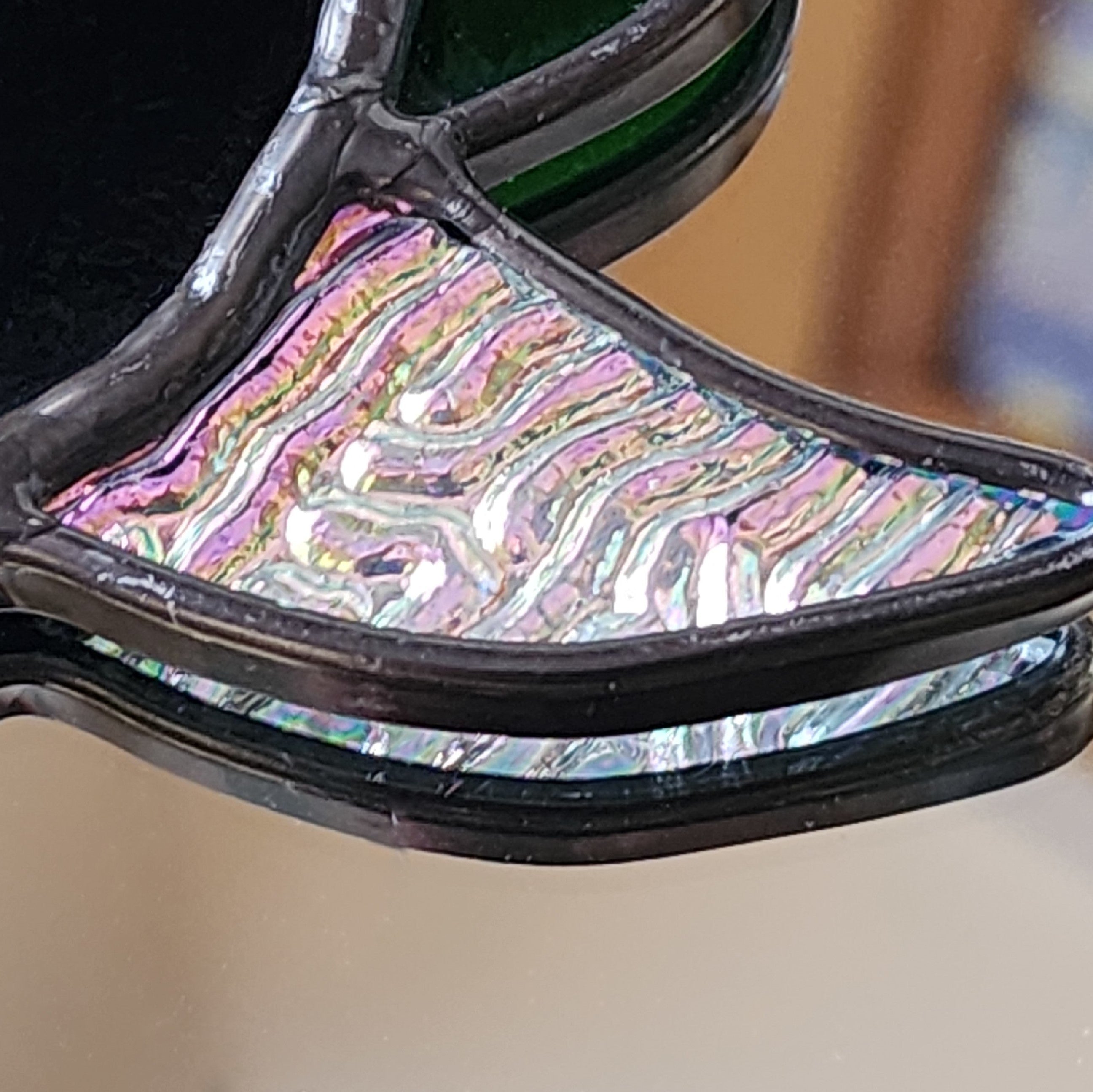 Close-up of a stained glass hummingbird wing with  vibrant, iridescent pink, purple, and silver 