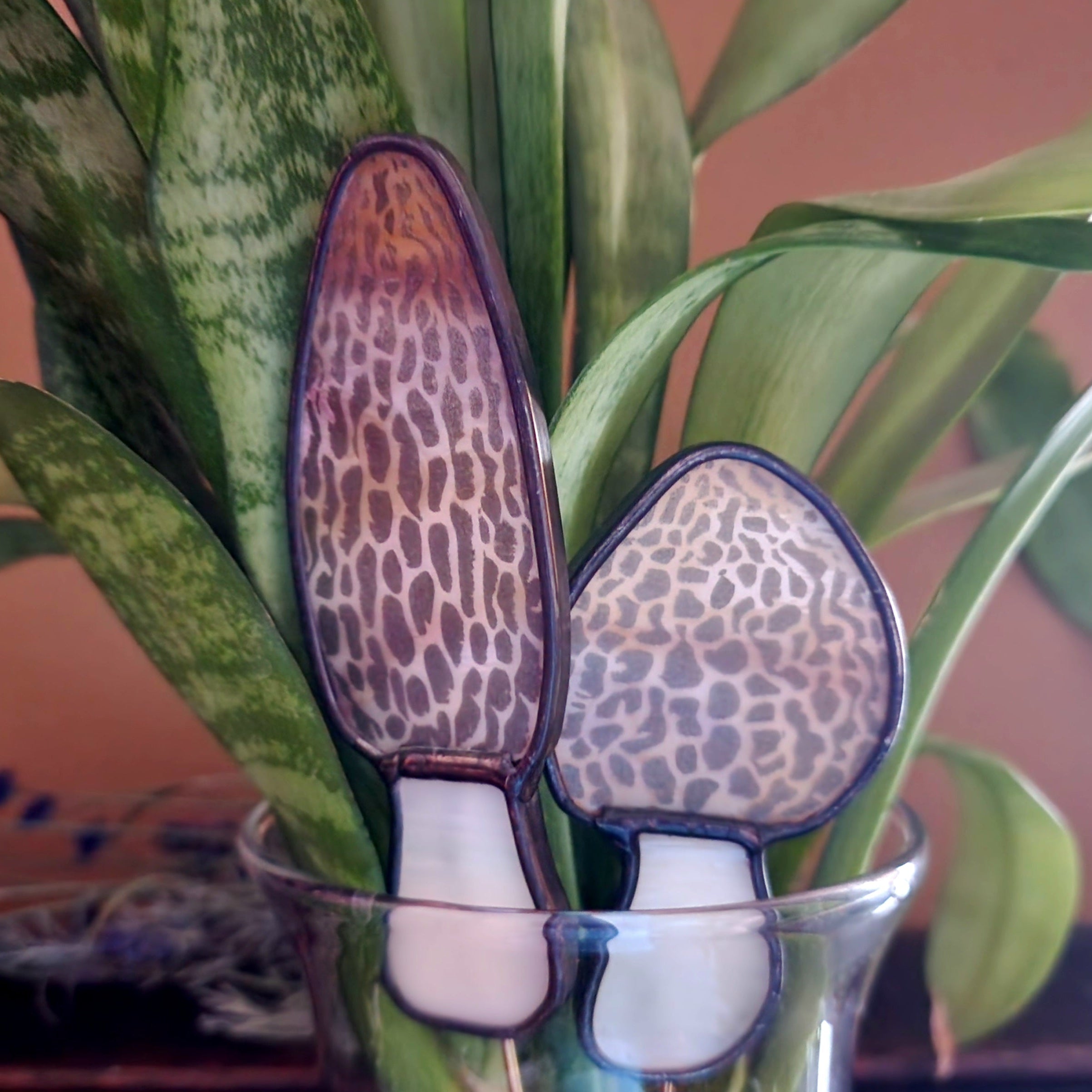 pair of morel mushroom stained glass plant stakes in a vase with snake plant